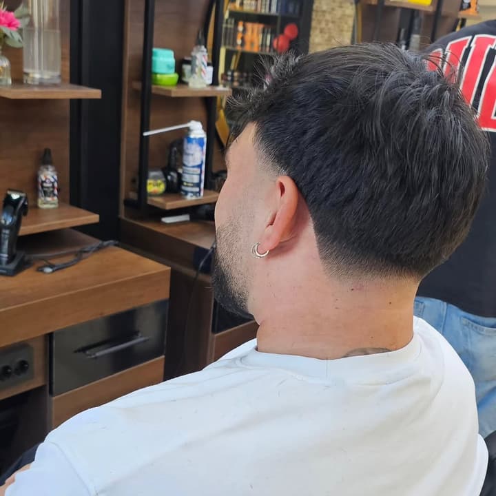 Taper Fade mit sauberem Übergang im Nacken und texturiertem Deckhaar, im Salon fotografiert