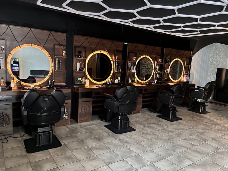 Die vier Plätze im Prince Barber Shop mit beleuchteten runden Spiegeln unter der sechseckigen LED-Lichtdecke